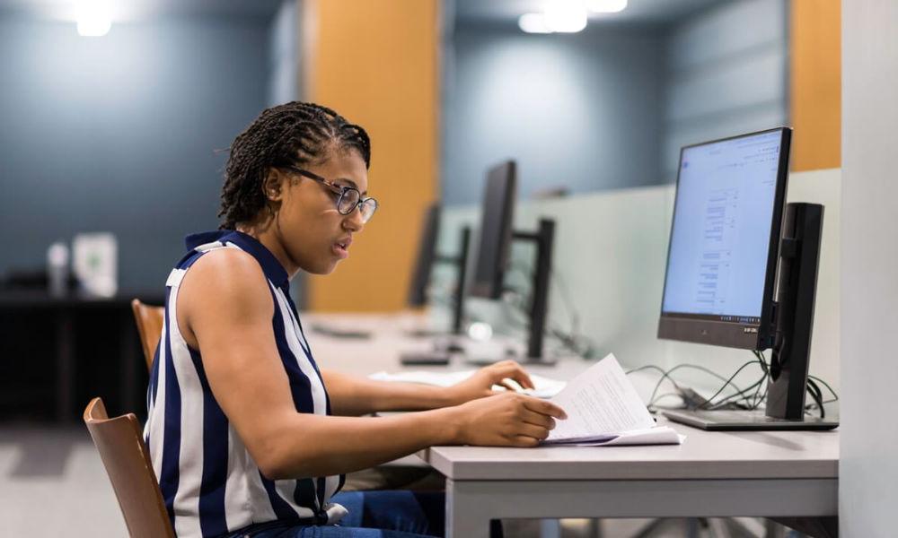 A woman at a desk with a laptop, focused on her work, representing academic life at the University of Rochester.