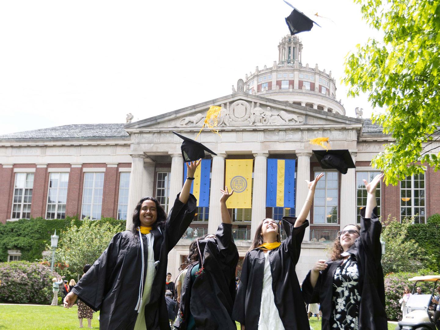 Graduates in traditional gowns and caps joyfully gather to commemorate their graduation at the University of Rochester.